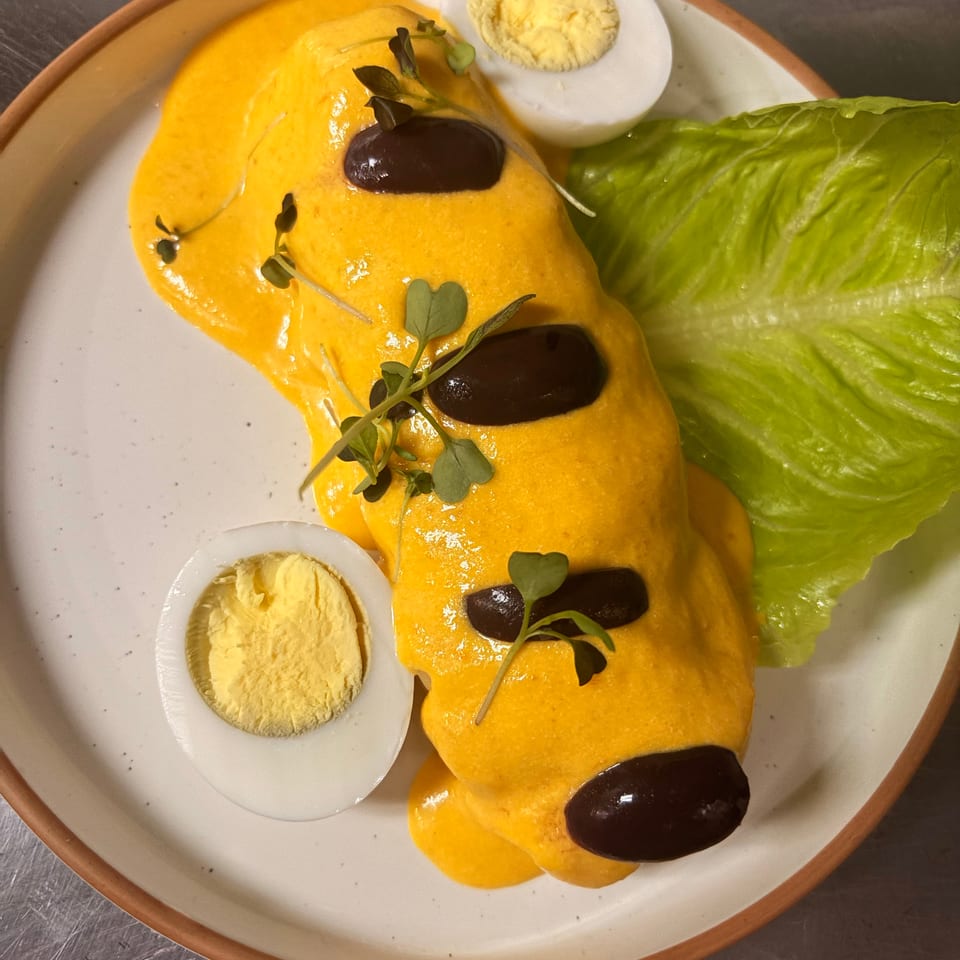 Plate of orange-sauced pasta topped with black olives and microgreens, served with romaine lettuce and dollops of mashed potatoes.
