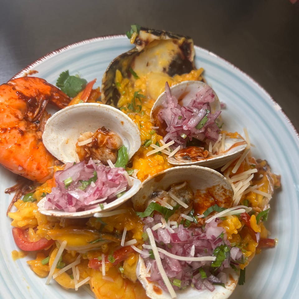 Seafood tacos with shrimp, clams, melted cheese, orange rice, pickled onions, cilantro, and shredded cheese on a plate.
