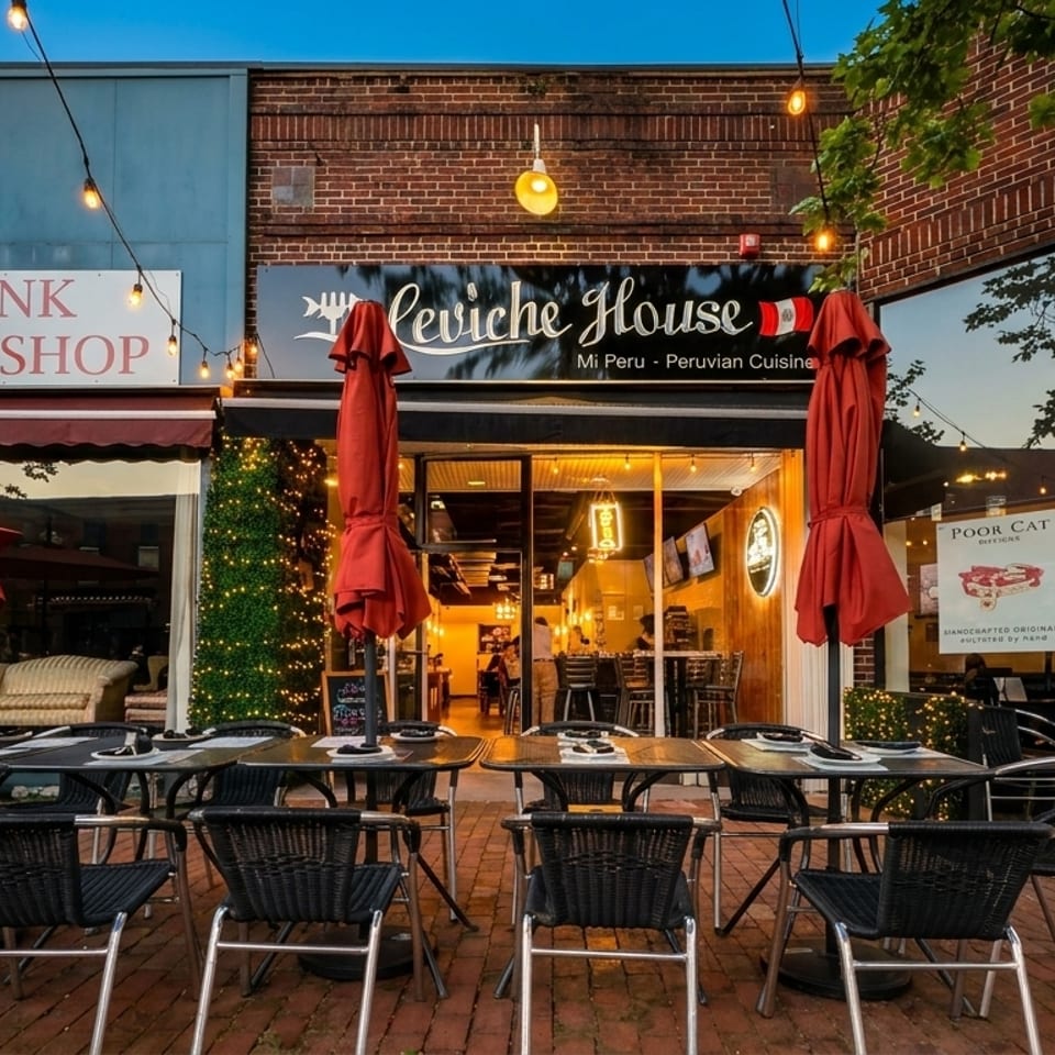 Outdoor patio seating with black tables and chairs in front of Ceviche House, a Peruvian restaurant.