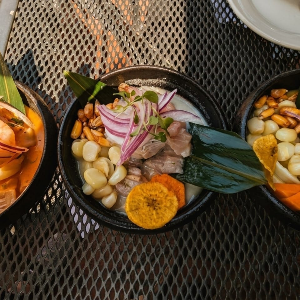 Three bowls of ceviche with shrimp, fish, corn, and plantain chips on a metal table.
